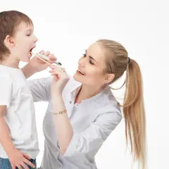 Lekarka bada gardło chłopca, używając patyczka do oceny języczka podniebiennego.