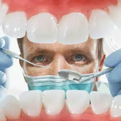 Lekarz od dziąseł bada zęby pacjenta, używając narzędzi dentystycznych. Widok z jamy ustnej.
