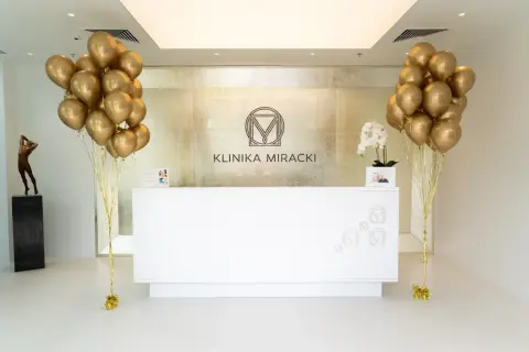 Recepcja kliniki z bukietami złotych balonów i rzeźbą.