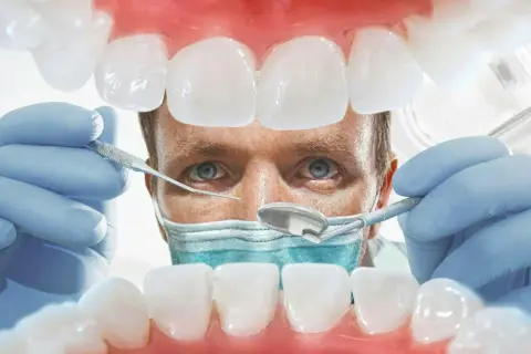 Lekarz od dziąseł bada zęby pacjenta, używając narzędzi dentystycznych. Widok z jamy ustnej.