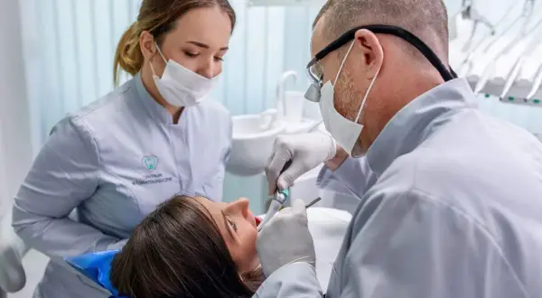 Dentysta leczy zęby pacjentki. Czy próchnica jest zaraźliwa? Warto zapytać specjalistę.