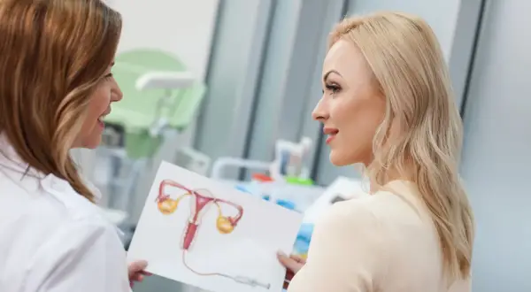 Lekarka pokazuje pacjentce schemat układu rozrodczego, omawiając atrofia w cytologii.