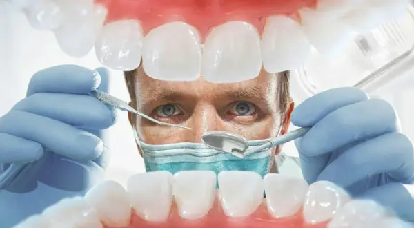 Lekarz od dziąseł bada zęby pacjenta, używając narzędzi dentystycznych. Widok z jamy ustnej.