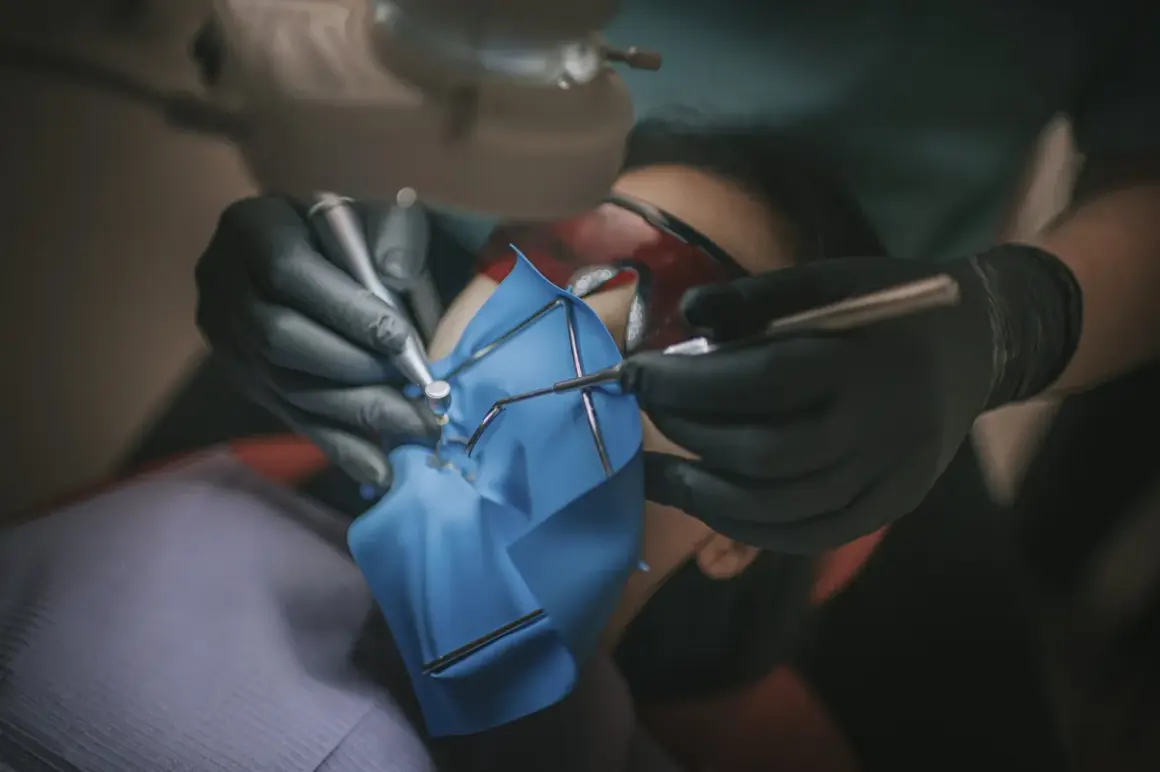 Precyzyjne leczenie kanałowe pod mikroskopem. Dentysta w rękawiczkach używa narzędzi do zabiegu.