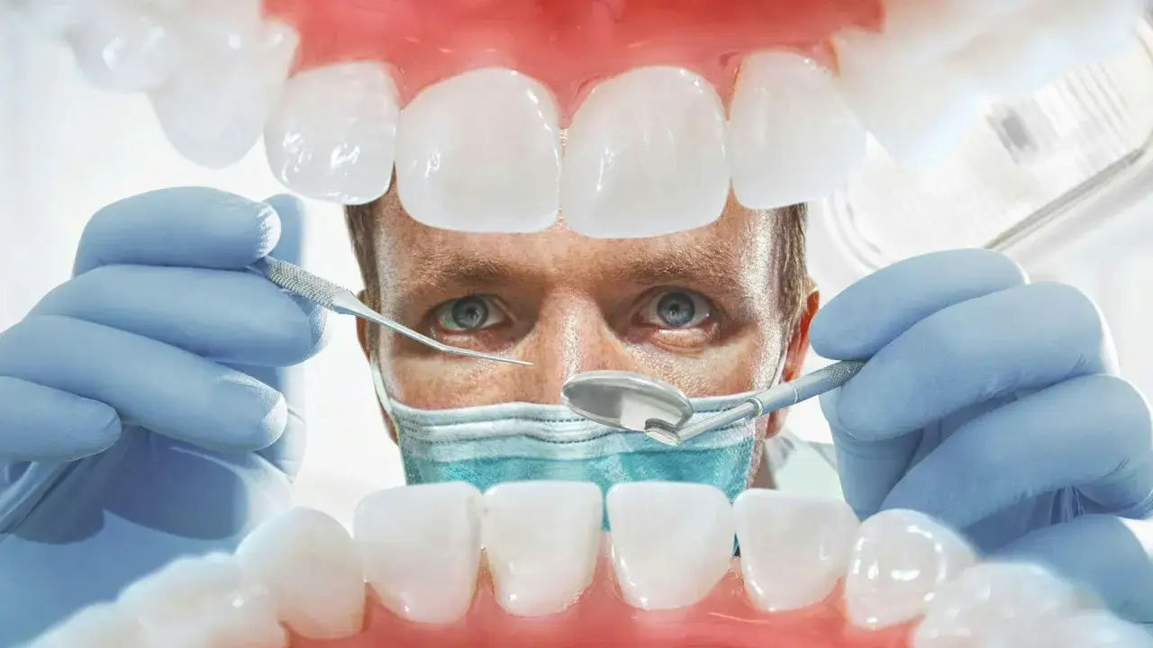 Lekarz od dziąseł bada zęby pacjenta, używając narzędzi dentystycznych. Widok z jamy ustnej.