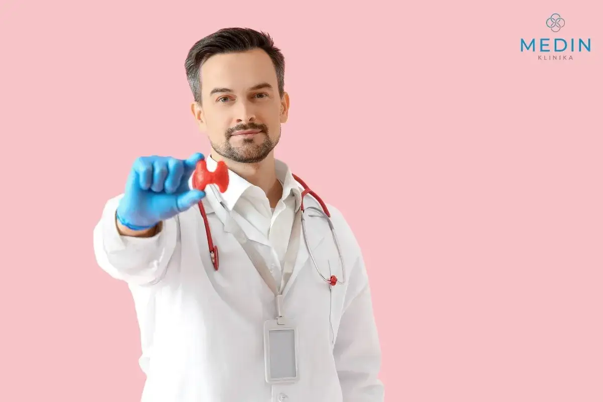 Lekarz w białym kitlu trzyma model tarczycy. Endokrynolog od czego? Od chorób tarczycy i innych zaburzeń hormonalnych.